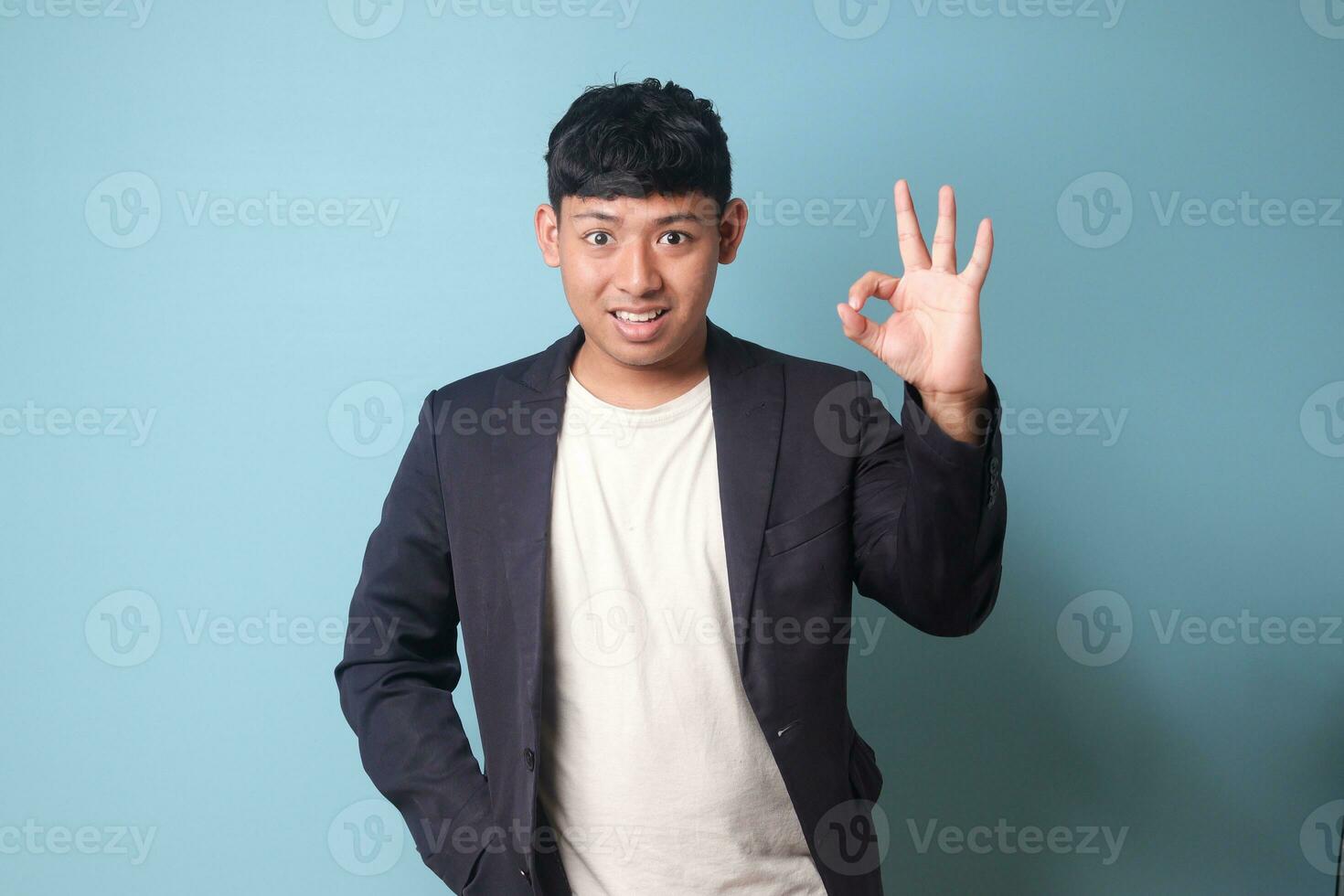 Porträt von jung asiatisch Geschäft Mann im beiläufig passen einverstanden beim etwas mit glücklich Ausdrücke. isoliert Bild auf Blau Hintergrund foto