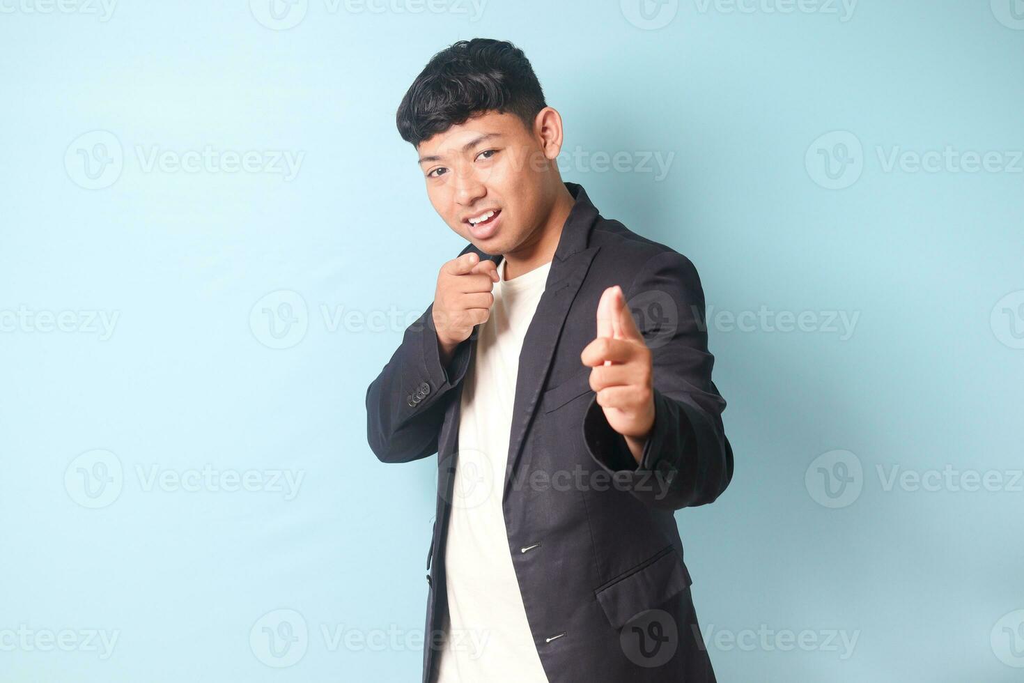 Porträt von jung asiatisch Geschäft Mann im beiläufig passen mit glücklich Ausdrücke während zeigen und suchen direkt beim Kamera. isoliert Bild auf Blau Hintergrund foto