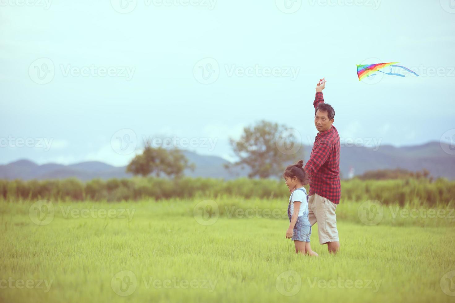 Kind und Vater spielen mit Drachen im Park foto