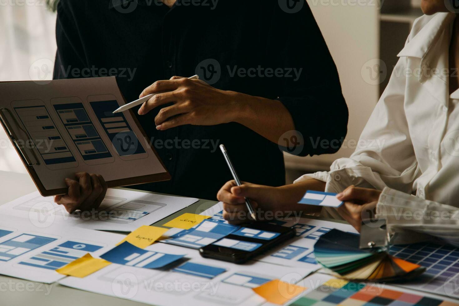 Nahaufnahme von UX-Entwicklern und UI-Designern beim Brainstorming über das Wireframe-Design der mobilen App-Schnittstelle auf dem Tisch mit Kundeninformationen und Farbcode in der Agentur für moderne digitale Entwicklung von Office.Creative foto