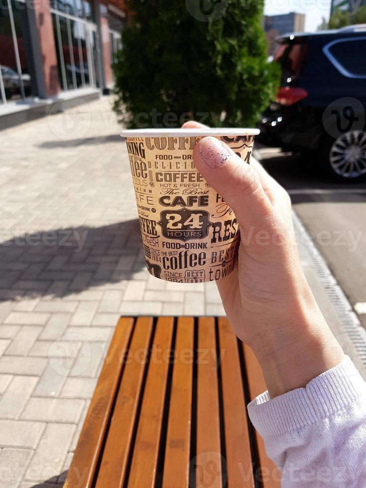 Kaffee in einem Pappbecher in einer Frauenhand auf der Straße foto