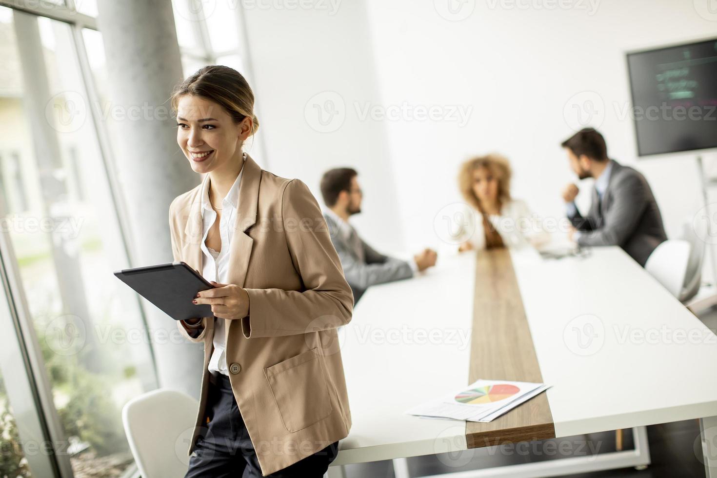 Frau, die eine Tafel mit einer Besprechung im Hintergrund hält foto