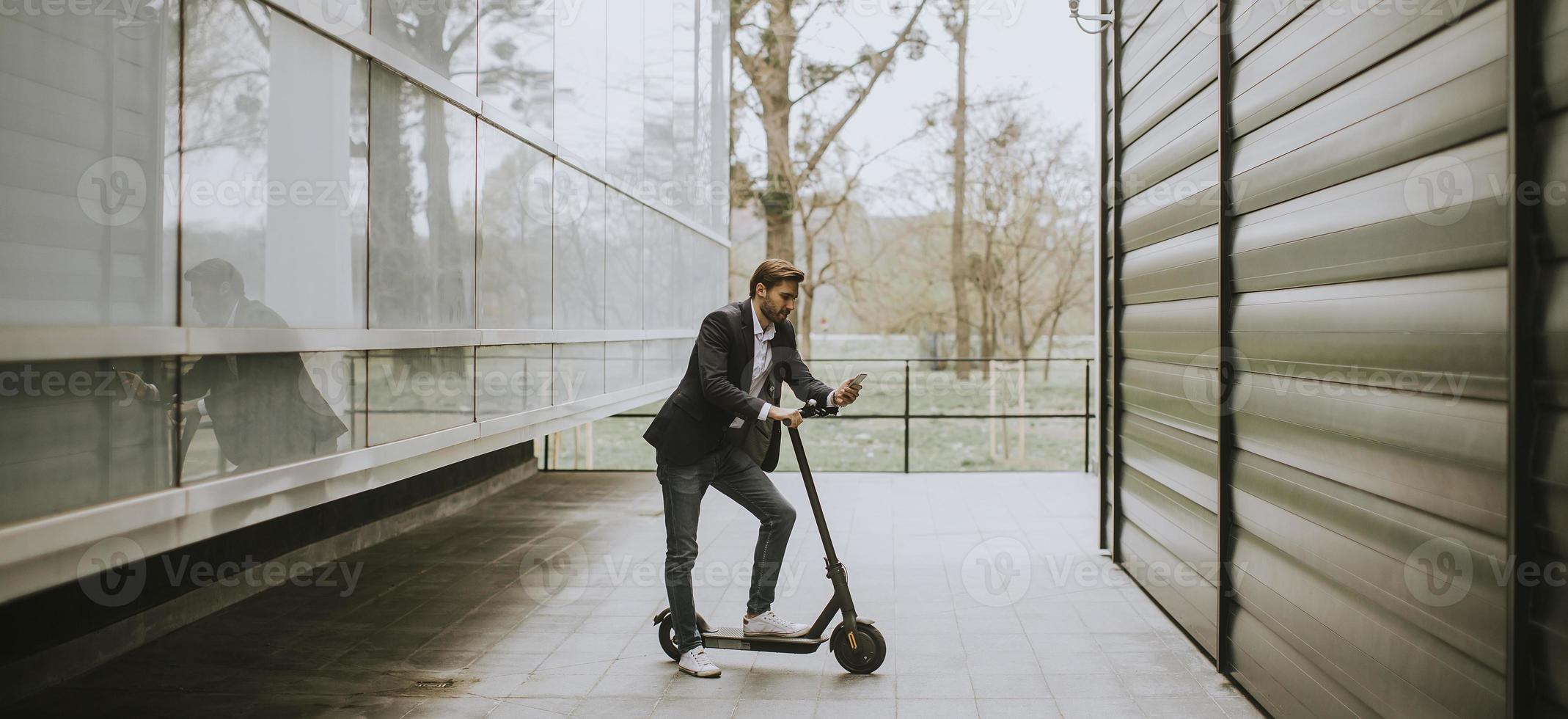 Mann, der auf Roller steht, während am Telefon foto