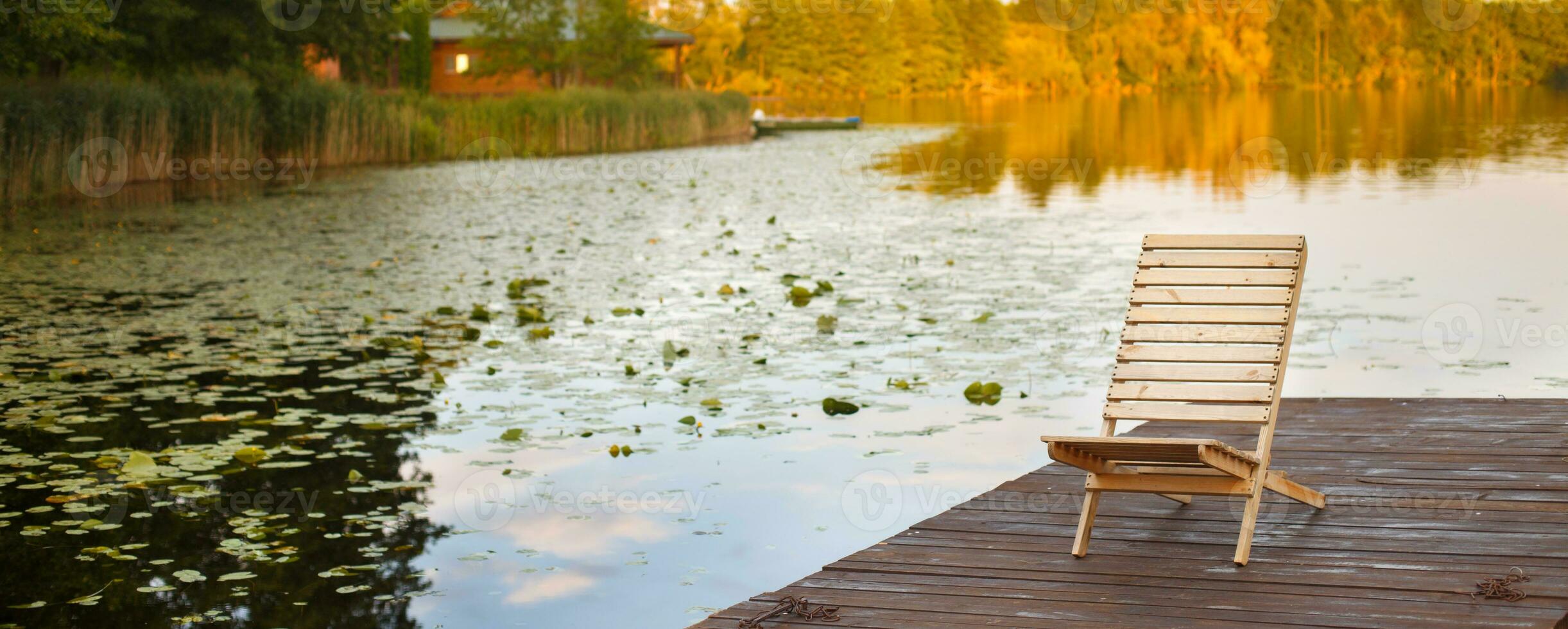 Holzsteg mit Liegestuhl am Steg am ruhigen See mitten im Wald foto