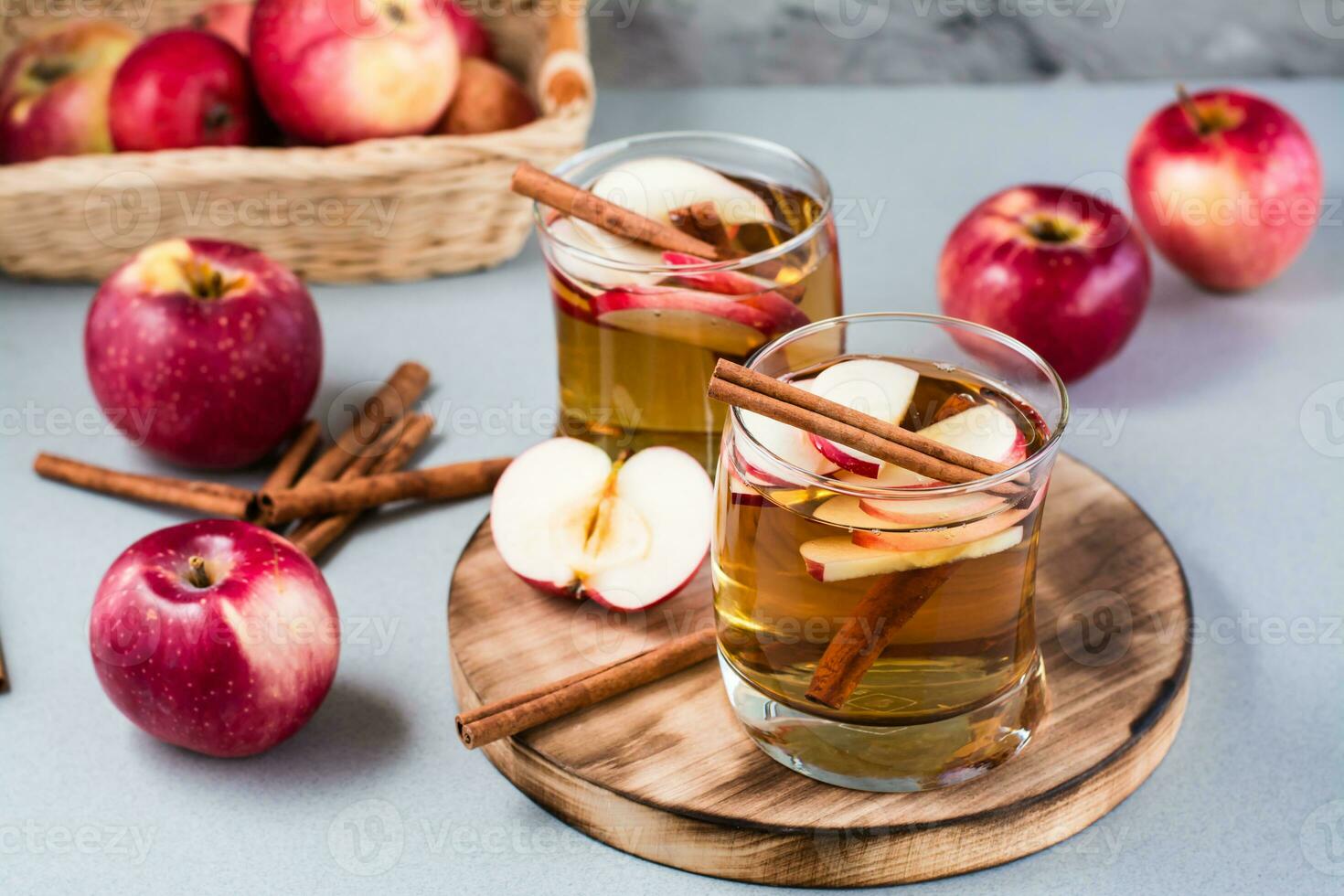 frisch organisch Apfel Apfelwein mit Zimt im Brille und Äpfel auf ein grau Hintergrund. Erwärmen Winter Getränke foto