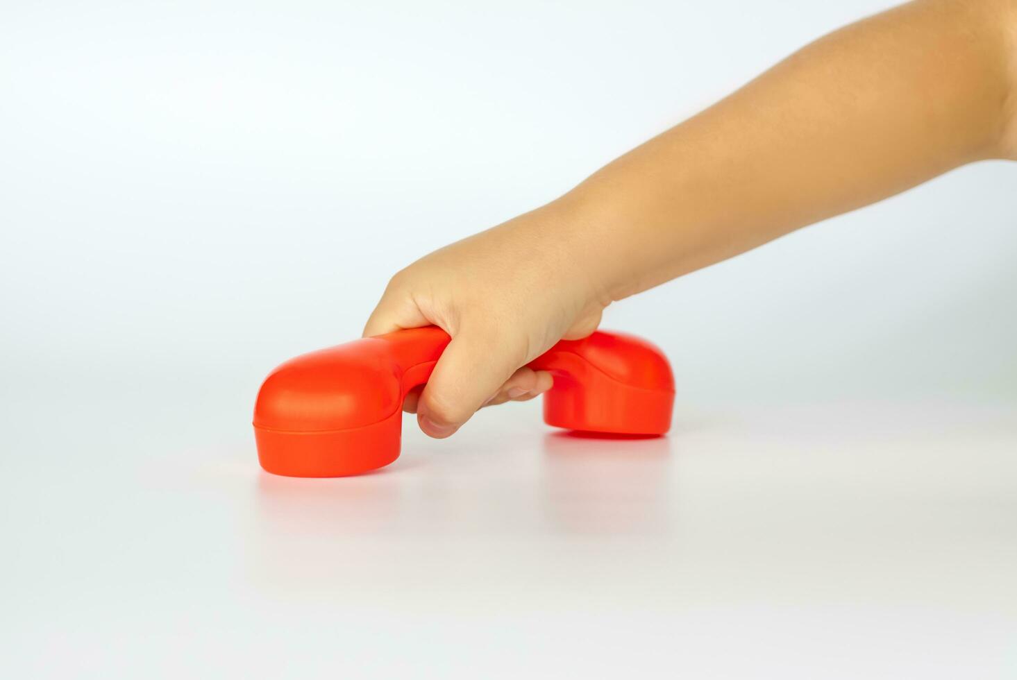 rot Spielzeug Telefon im das Kinder Hand. Nahansicht von ein Kinder Hand. isoliert auf ein Weiß Hintergrund. das Konzept von ein Werbung Banner. foto