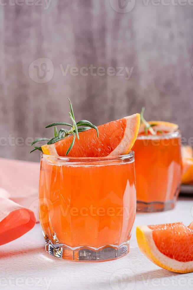 frisch Grapefruit Saft mit Rosmarin und Stücke von Obst im Brille auf das Tabelle Vertikale Aussicht foto