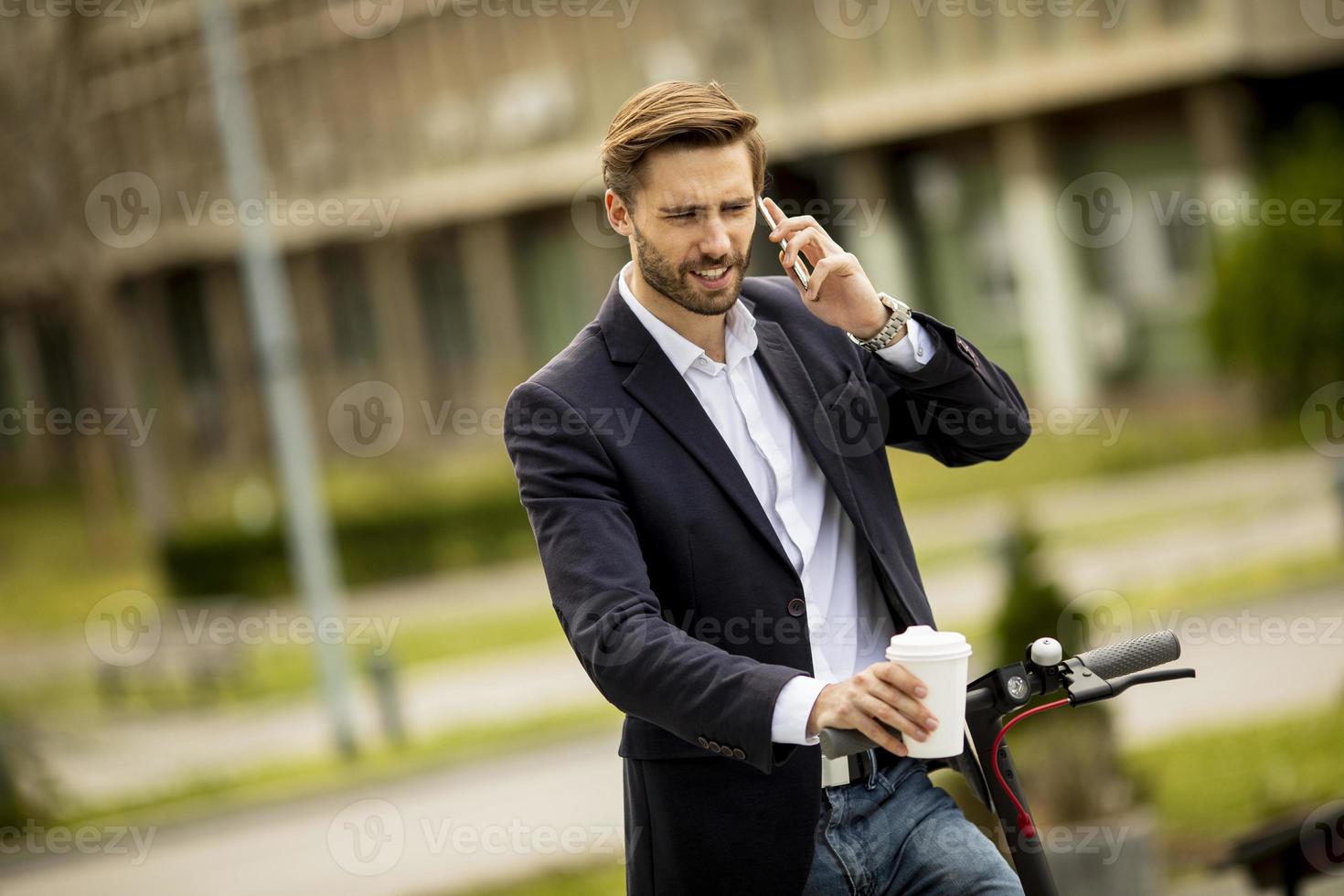 Mann, der auf einem Roller anhält, um einen Anruf anzunehmen foto