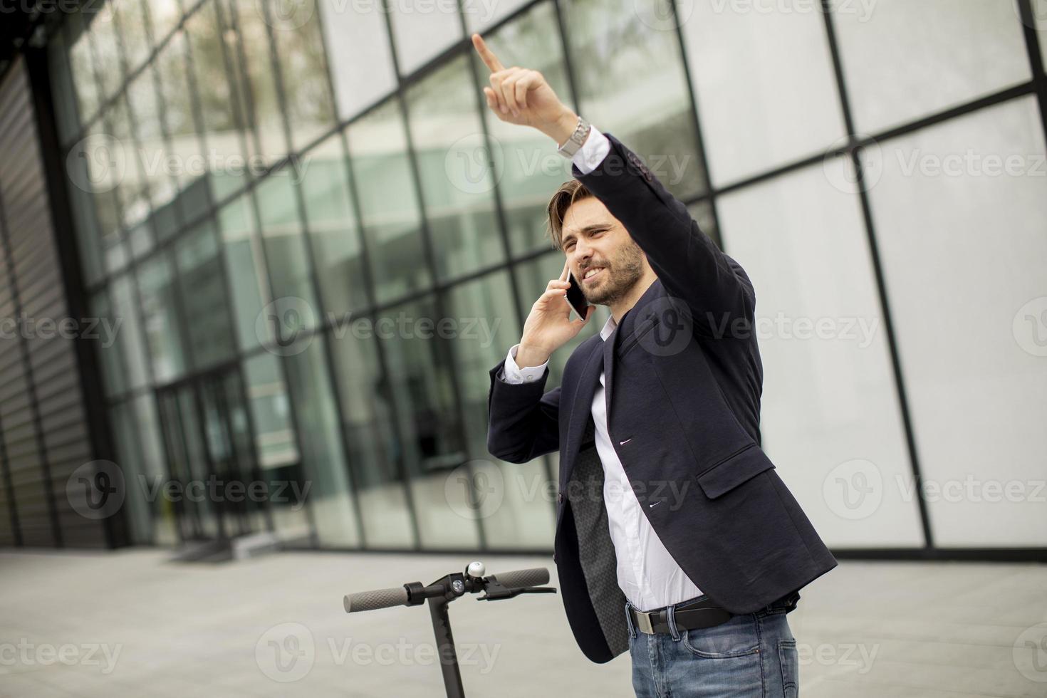 Gelegenheitsgeschäftsmann auf einem Roller, der am Telefon spricht und zeigt foto