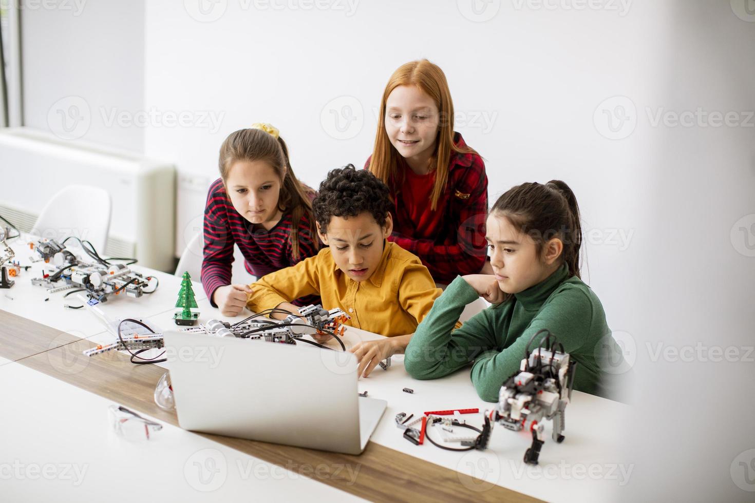 glückliche Kinder, die elektrisches Spielzeug und Roboter im Robotikklassenzimmer programmieren foto