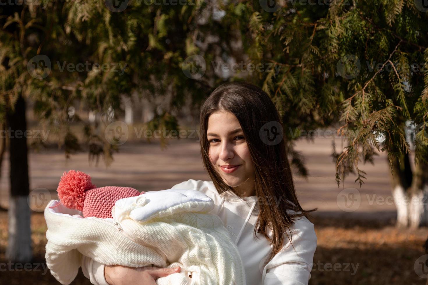 hübsche junge Frau, die ein neugeborenes Baby in ihren Armen hält foto