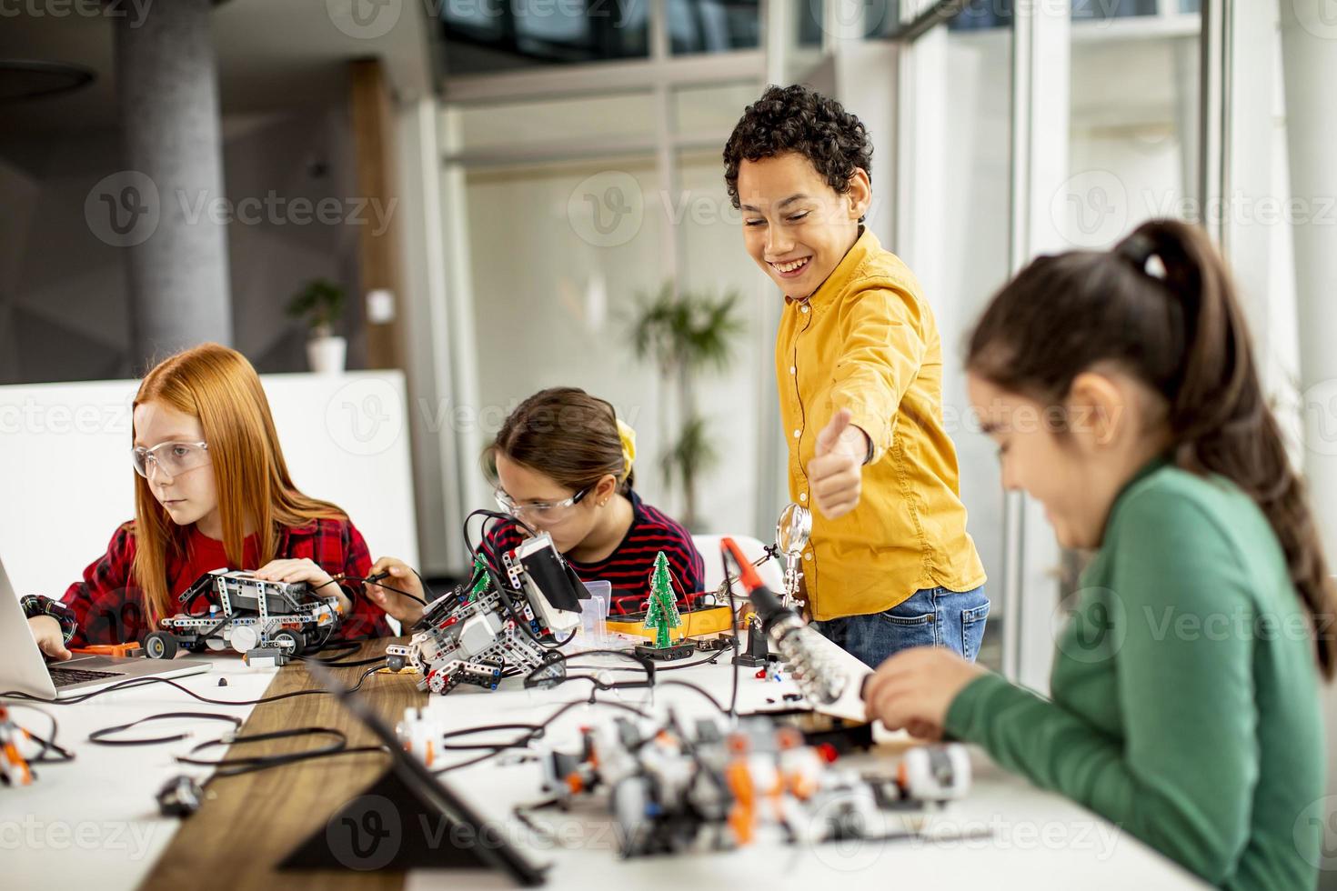 glückliche Kinder, die elektrisches Spielzeug und Roboter im Robotikklassenzimmer programmieren foto