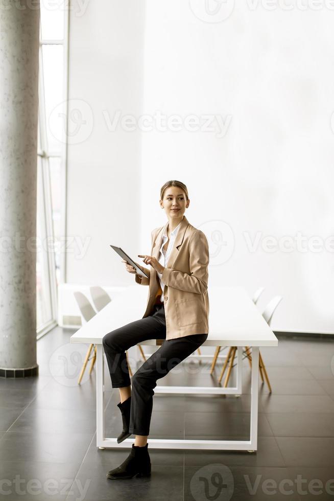 junge Frau, die digitales Tablett im modernen Büro hält foto