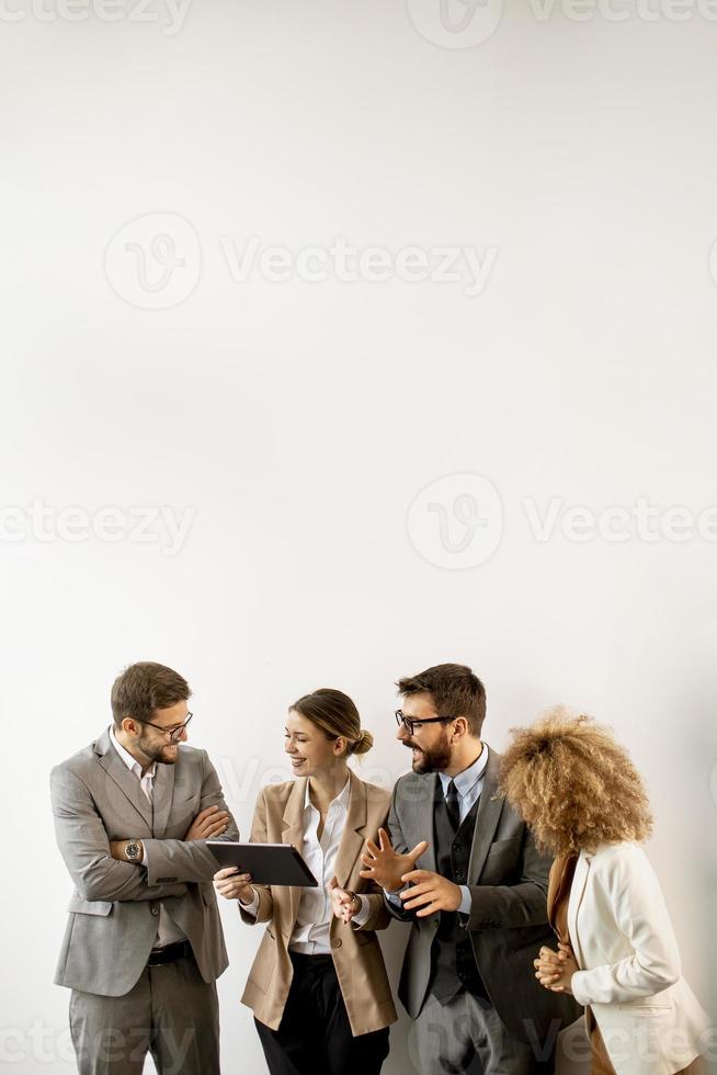 Multiethnische Geschäftsleute, die digitales Tablet verwenden, während sie an der Wand im Büro stehen foto