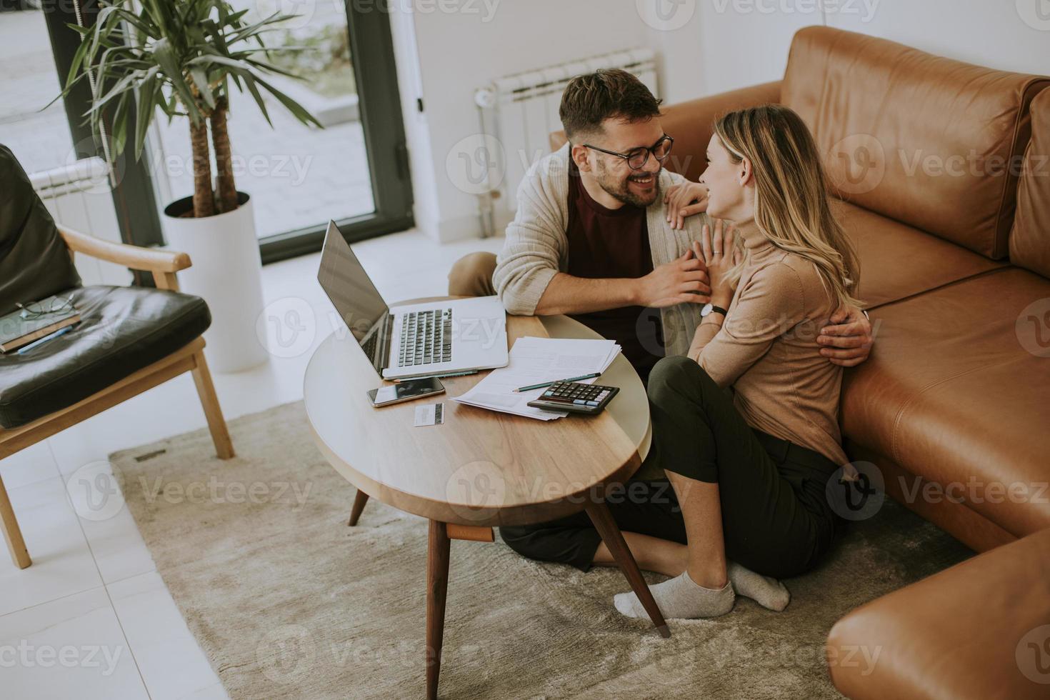 junge Frau und junger Mann mit Laptop beim Sitzen am Sofa zu Hause foto