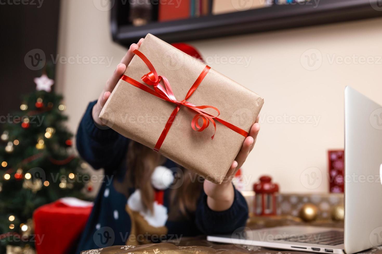 Frau, die Geschenkbox mit rotem Band auf einem Weihnachtshintergrund hält foto