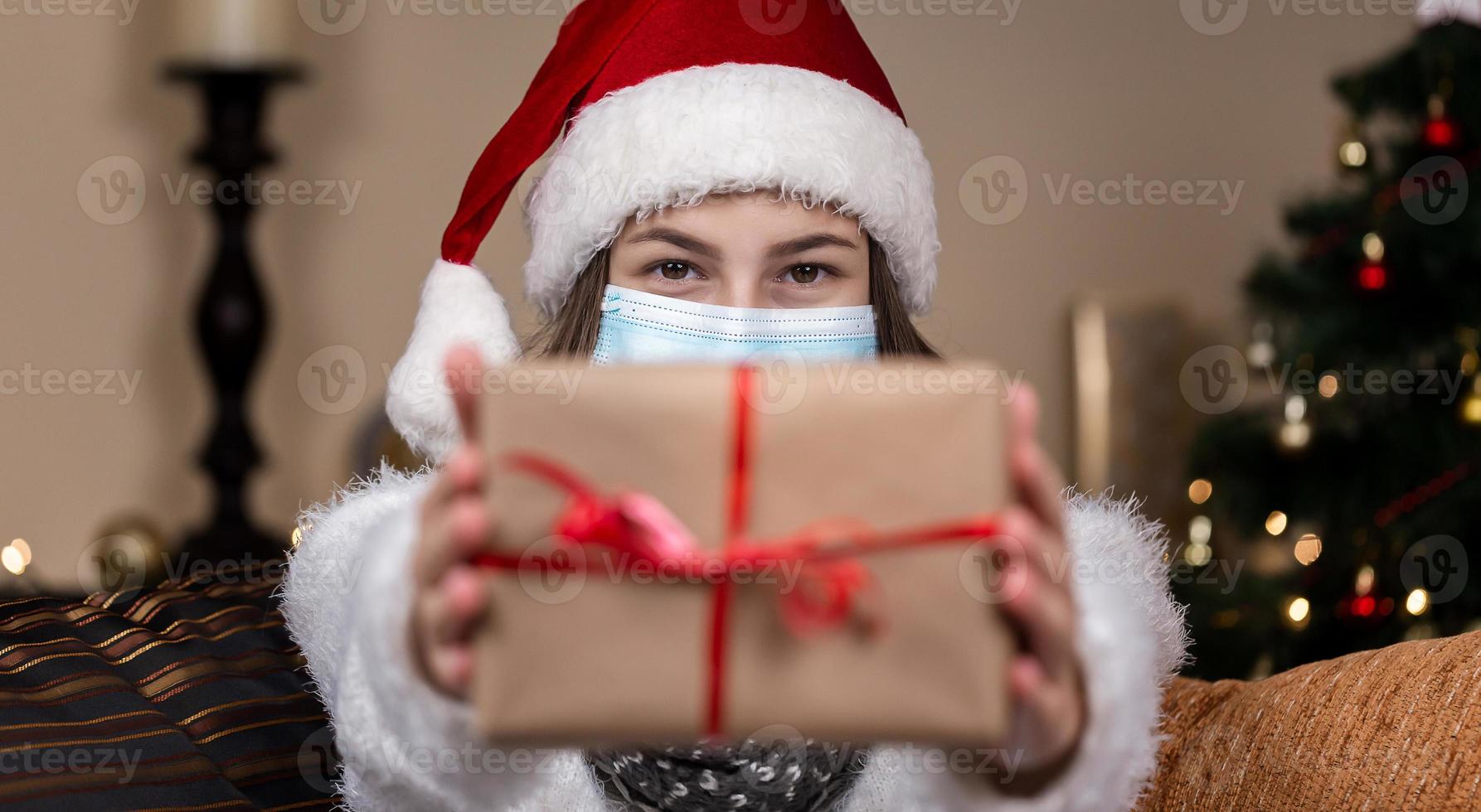 Frau, die Geschenkbox mit rotem Band auf einem Weihnachtshintergrund hält foto