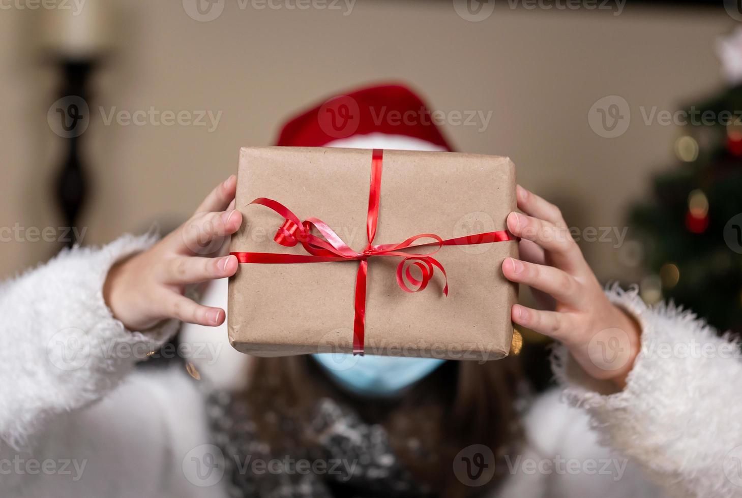 gesichtsloses Porträt einer Frau, die Geschenkbox mit rotem Band an Weihnachten hält foto