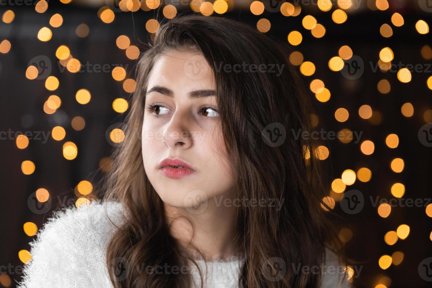 Nahaufnahmeporträt einer sehr schönen jungen Frau auf Weihnachten Bokeh beleuchtet Hintergrund attraktives weibliches Porträt drinnen Porträt der hübschen Frau mit warmen Lichterketten festlichen Feiertagen foto