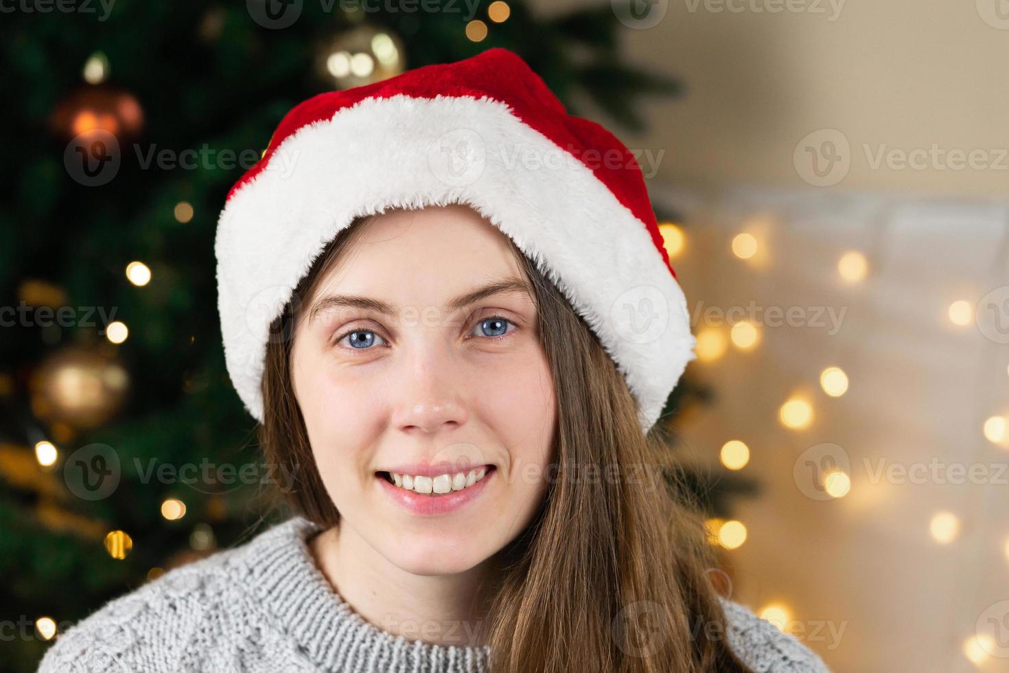 Porträt einer jungen Frau in einem grauen Pullover und Weihnachtsmannhut foto