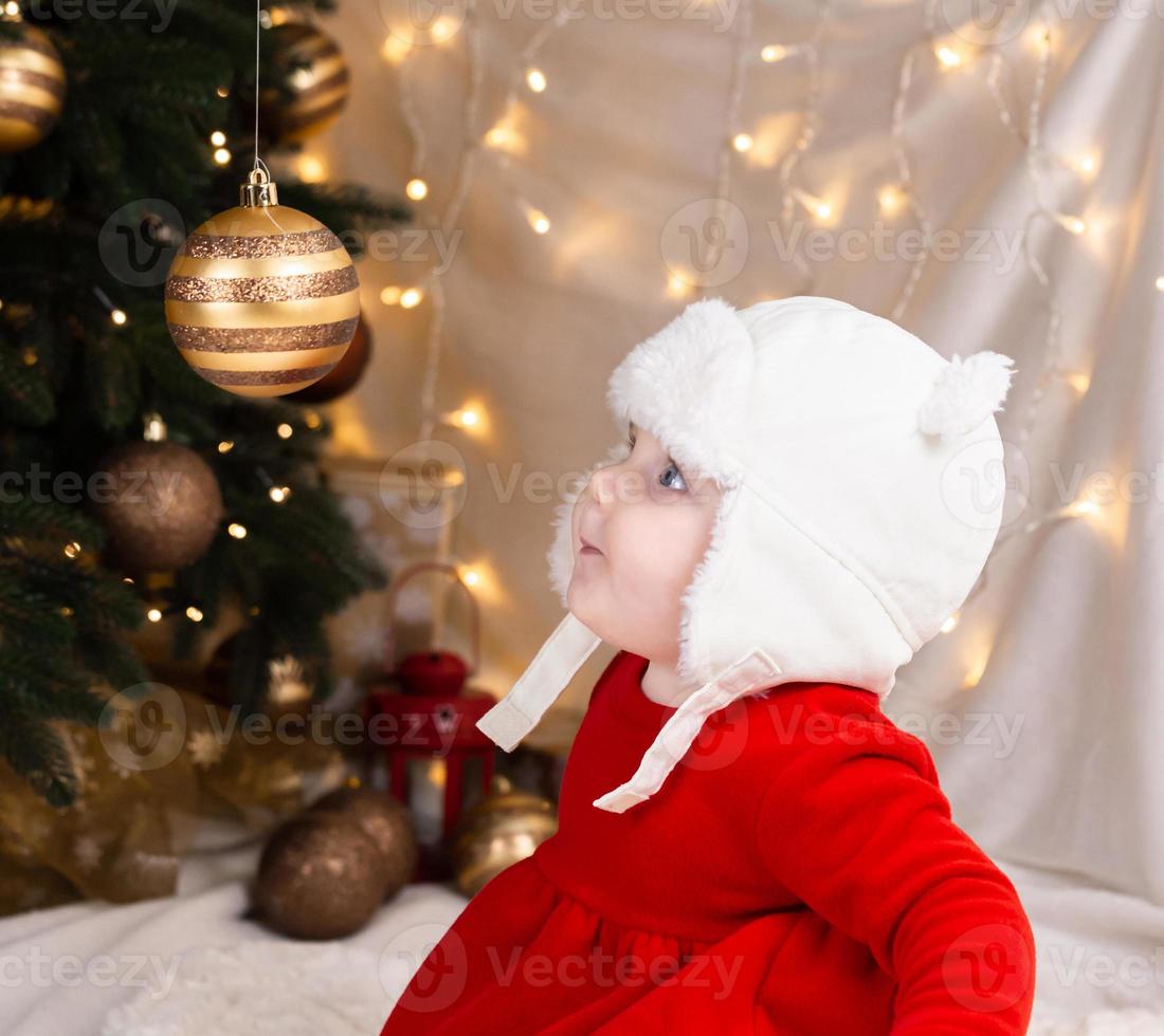 Baby schaut auf einen Weihnachtsbaumball foto