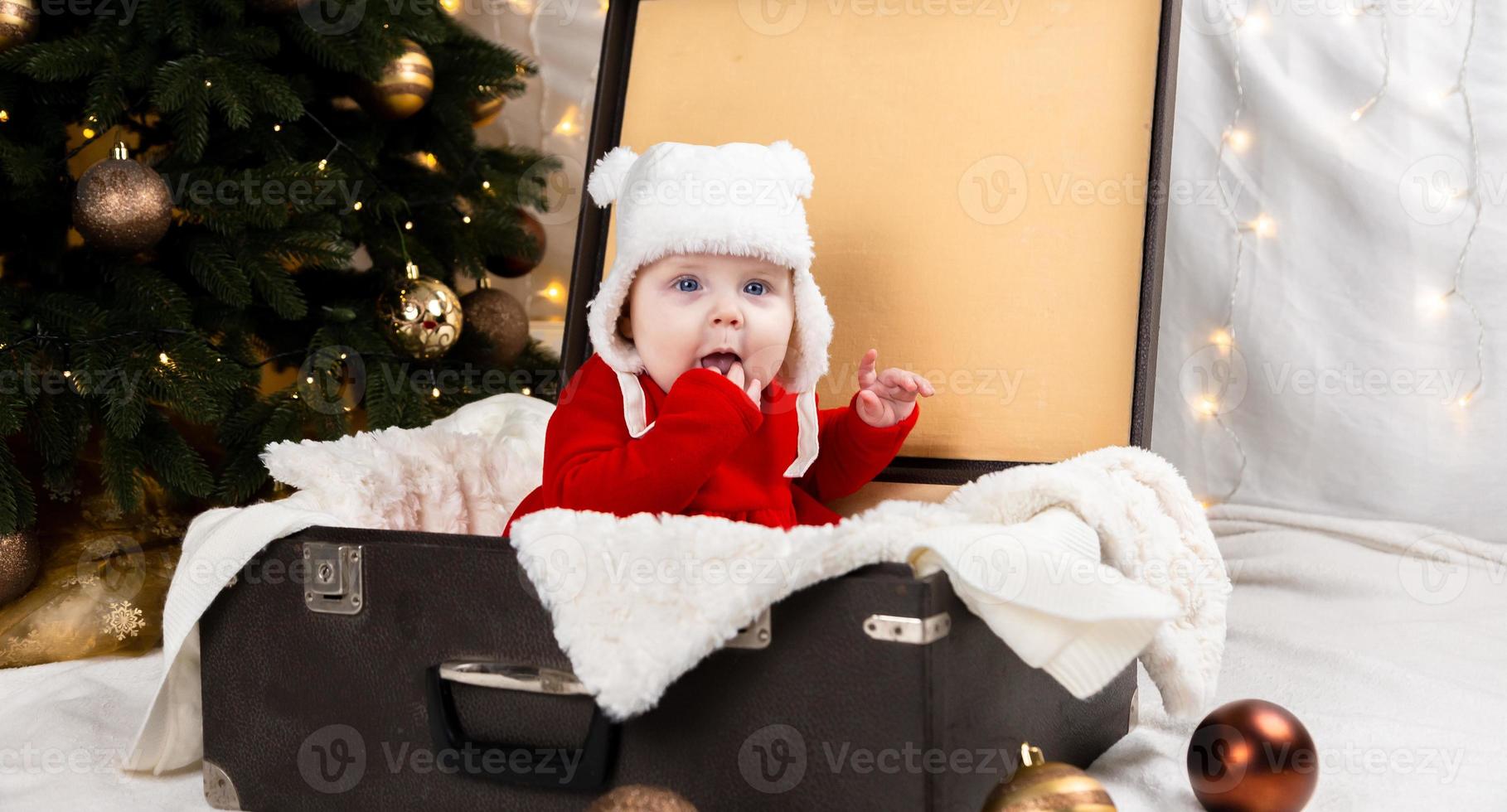 Das Baby sitzt in einem alten Koffer foto