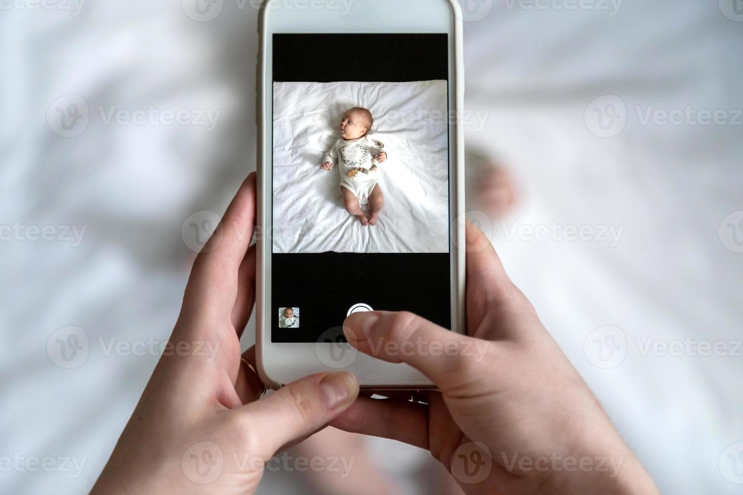 über dem hohen Winkelschuss der glücklichen Mutter, die ihr Baby oder Mädchen fotografiert foto