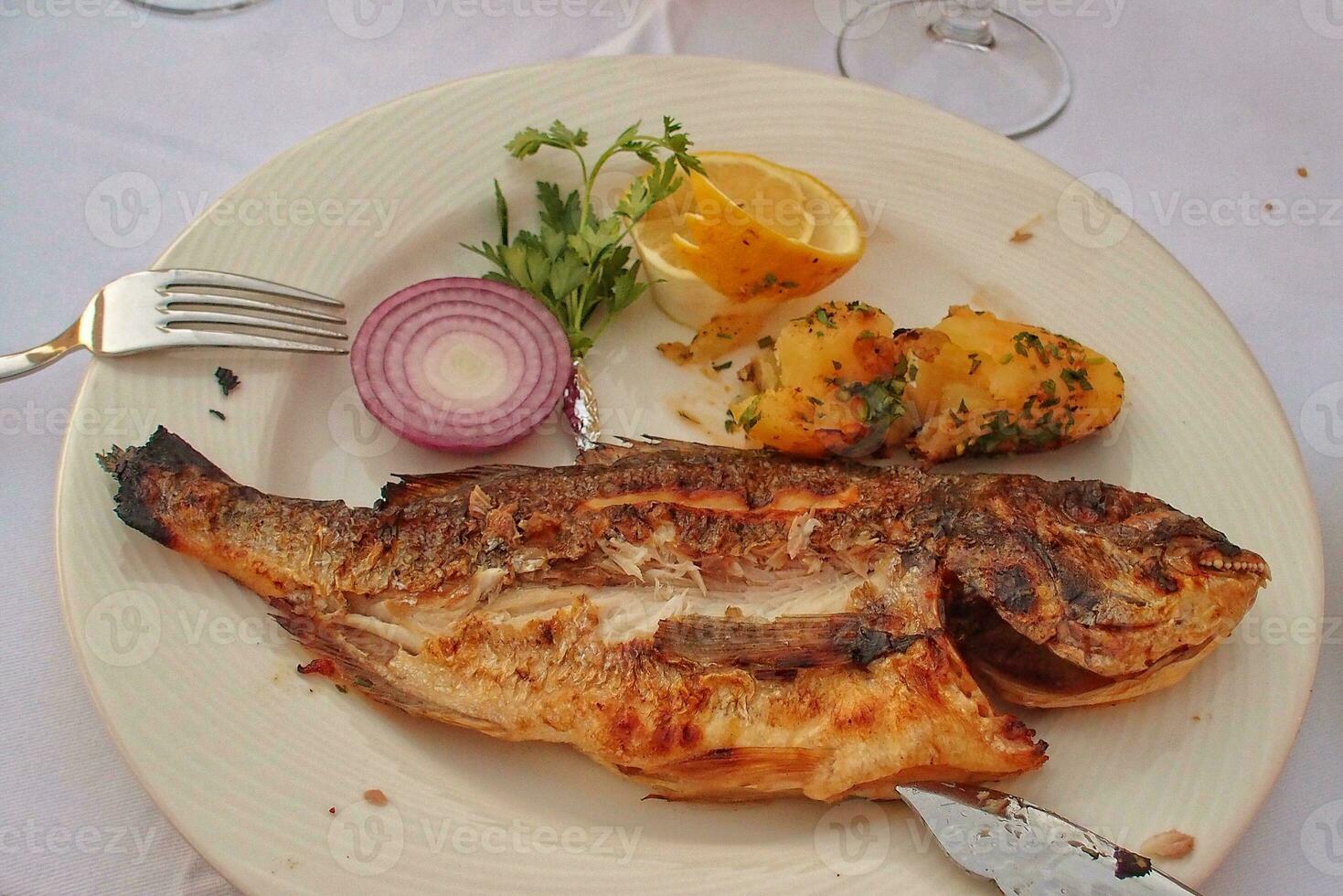 lecker groß gegrillt Fisch auf ein Weiß Teller mit Gemüse foto
