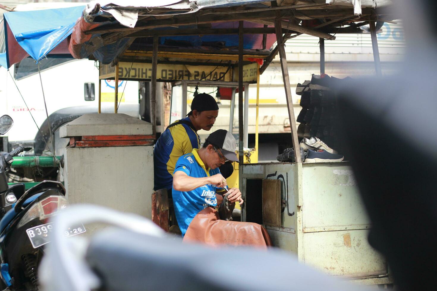 Mist, Indonesien - - 2022. Schuh Sohle, einzig, alleinig Arbeiter reparieren Schuhe beim ein Straßenrand Stand. ein einzigartig Beruf von Indonesien. foto