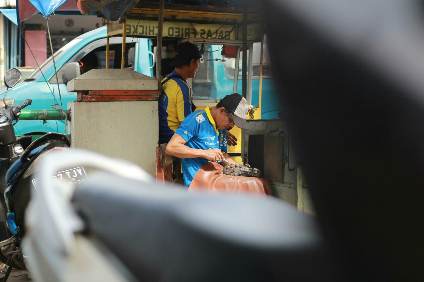 Mist, Indonesien - - 2022. Schuh Sohle, einzig, alleinig Arbeiter reparieren Schuhe beim ein Straßenrand Stand. ein einzigartig Beruf von Indonesien. foto