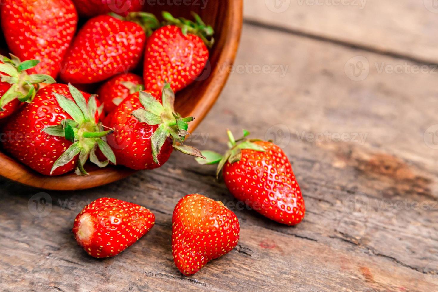 Holzschale voller frischer Erdbeeren auf dem braunen Tisch foto