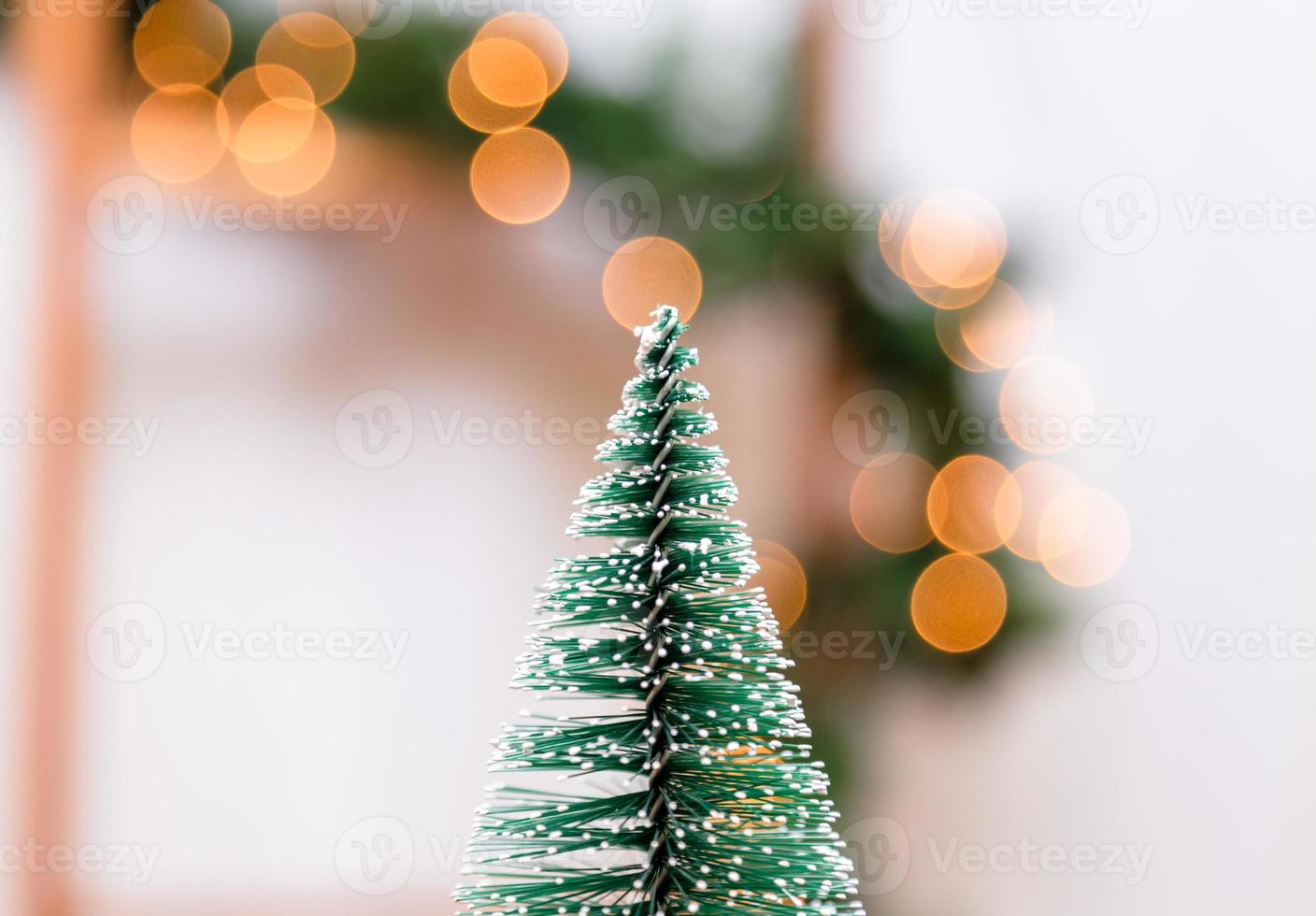 Miniatur-Weihnachtsbaum auf dem unscharfen Hintergrund mit Weihnachtslichtern foto