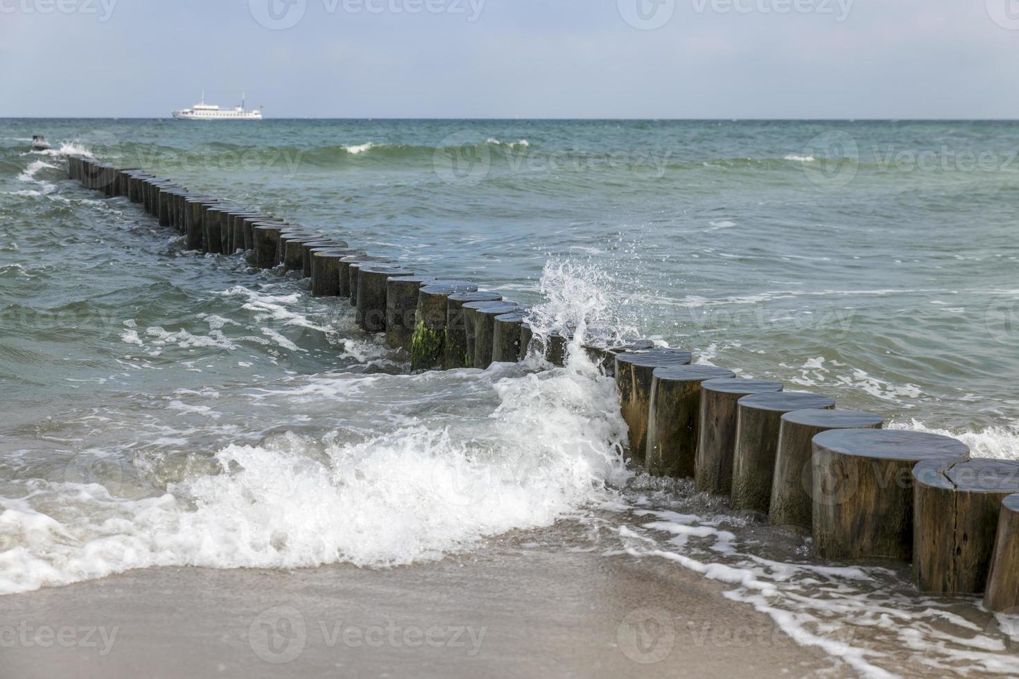 Wellen wuschen sich um Baumstämme an der Ostseeküste im Sand foto