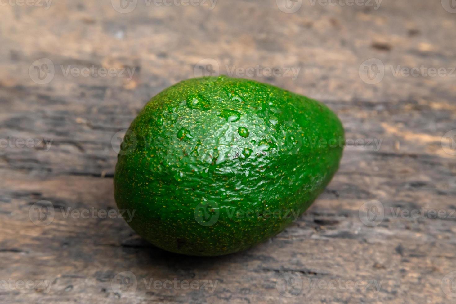 ganze frische Avocado in der Holzplatte auf dunklem hölzernem Tischhintergrund foto