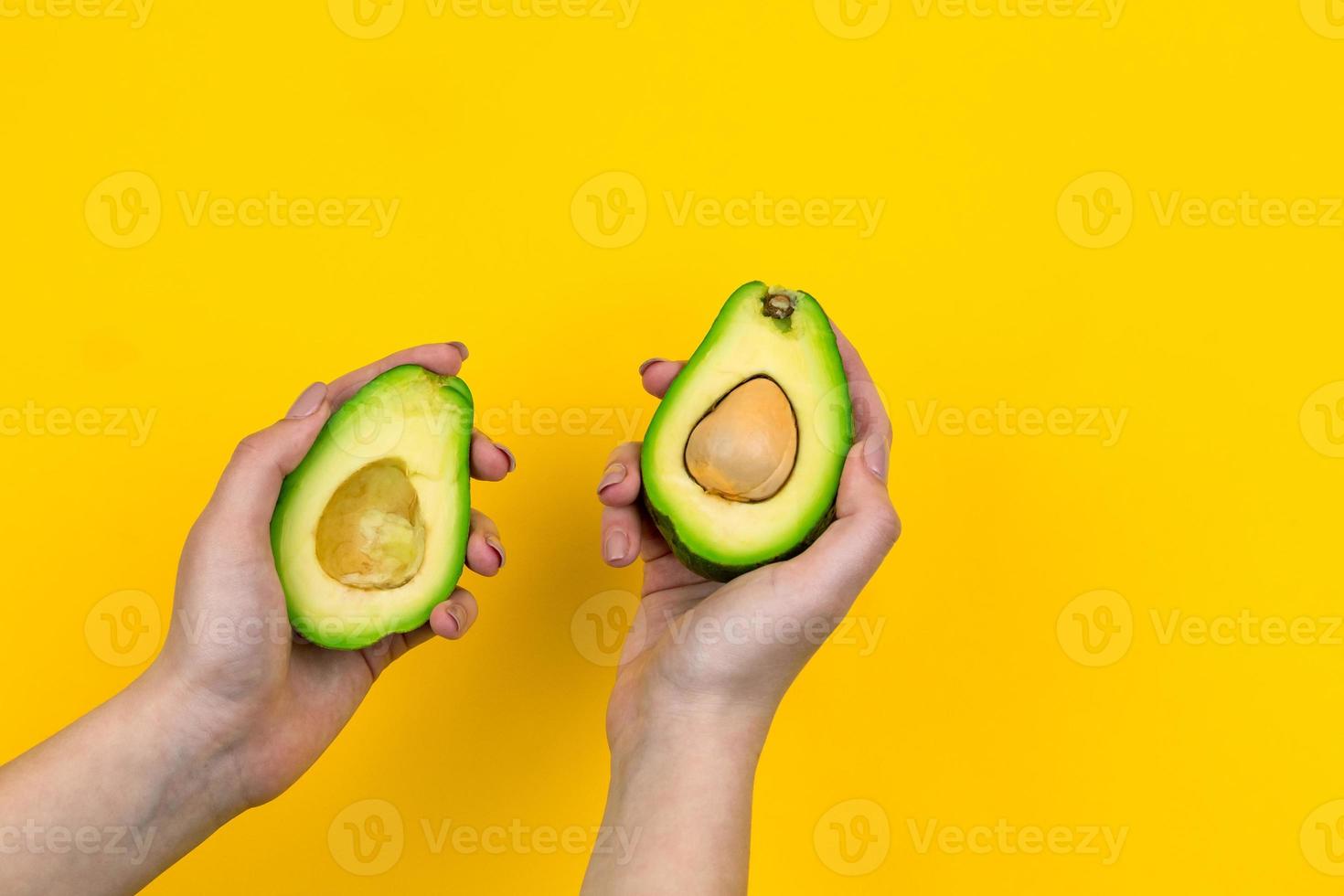 Avocado in einer weiblichen Hand ist auf einem gelben Hintergrund isoliert foto