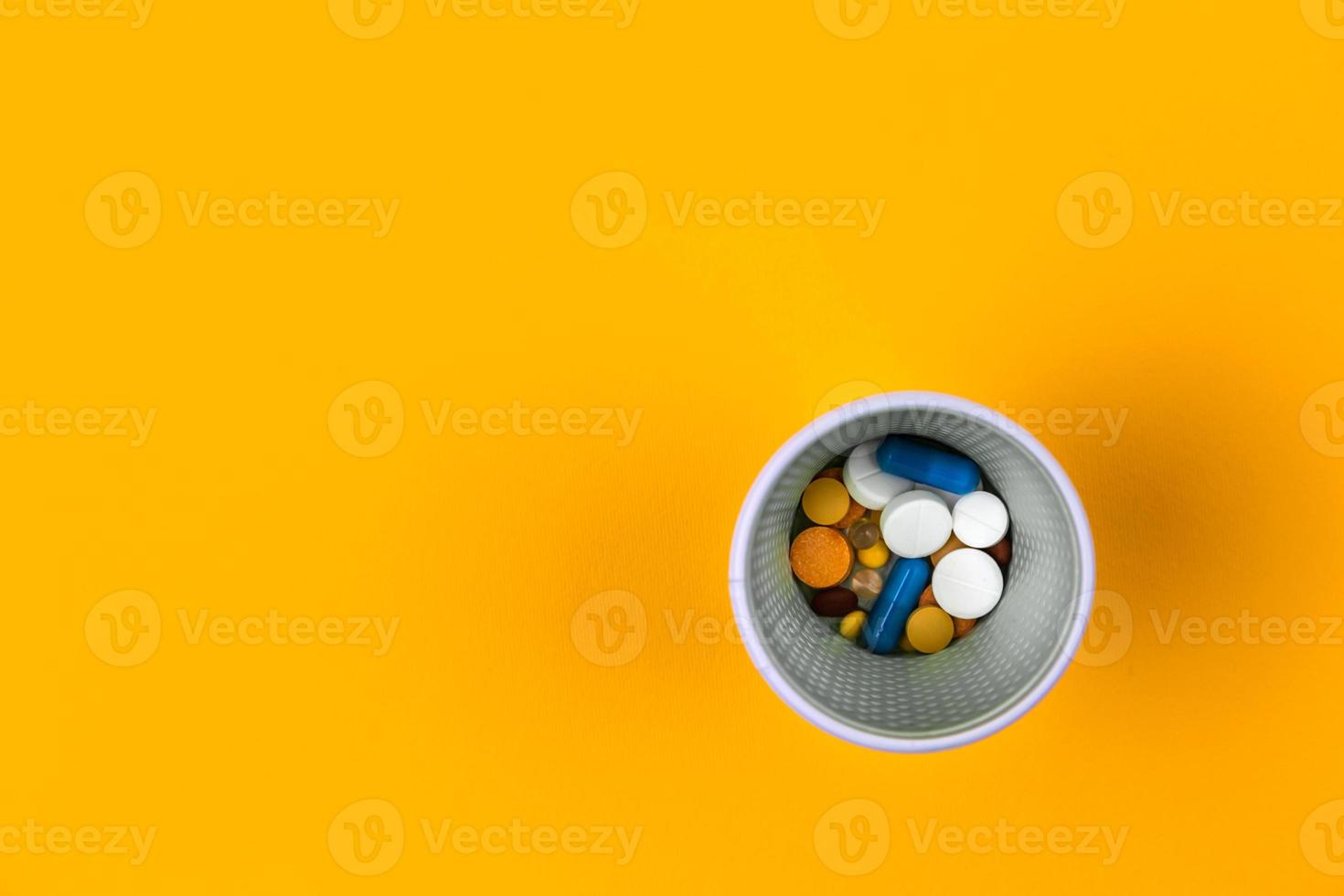 bunte Pillen oder Tabletten im Glas auf gelbem Hintergrund foto