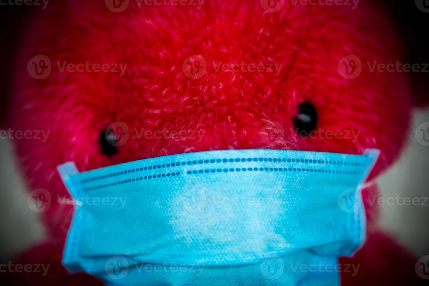 einsamer roter Teddybär in einer medizinischen Schutzmaske foto