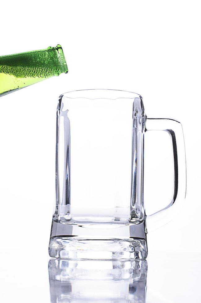 grüne Flaschen gießen in leeres Bierglas foto