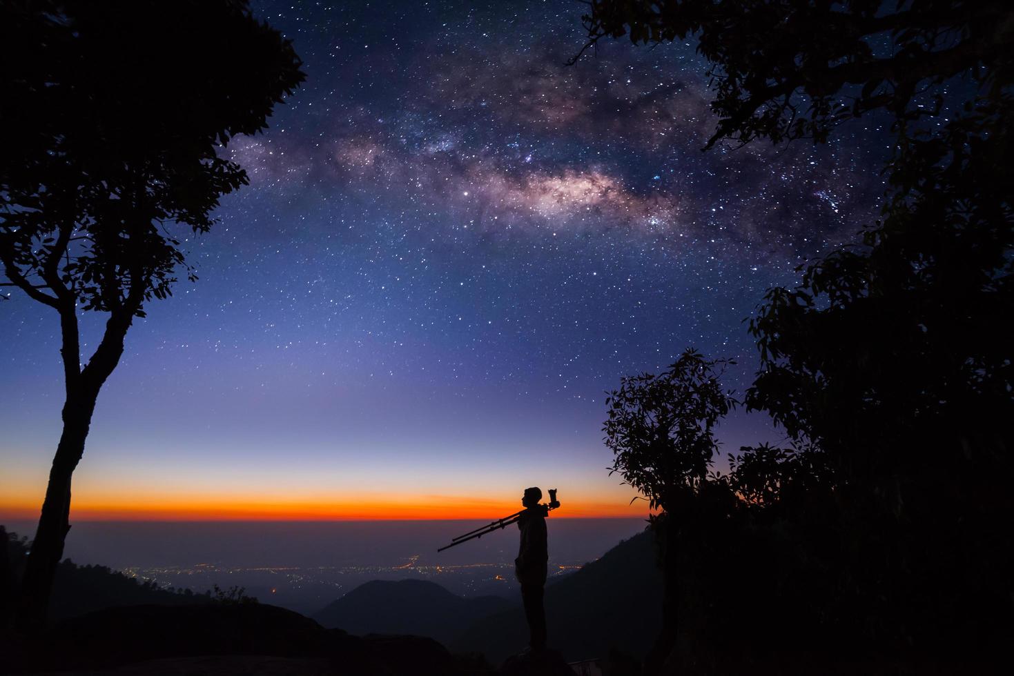 Silhouette eines professionellen Fotografen, der die Milchstraße in den Bergen fotografiert foto