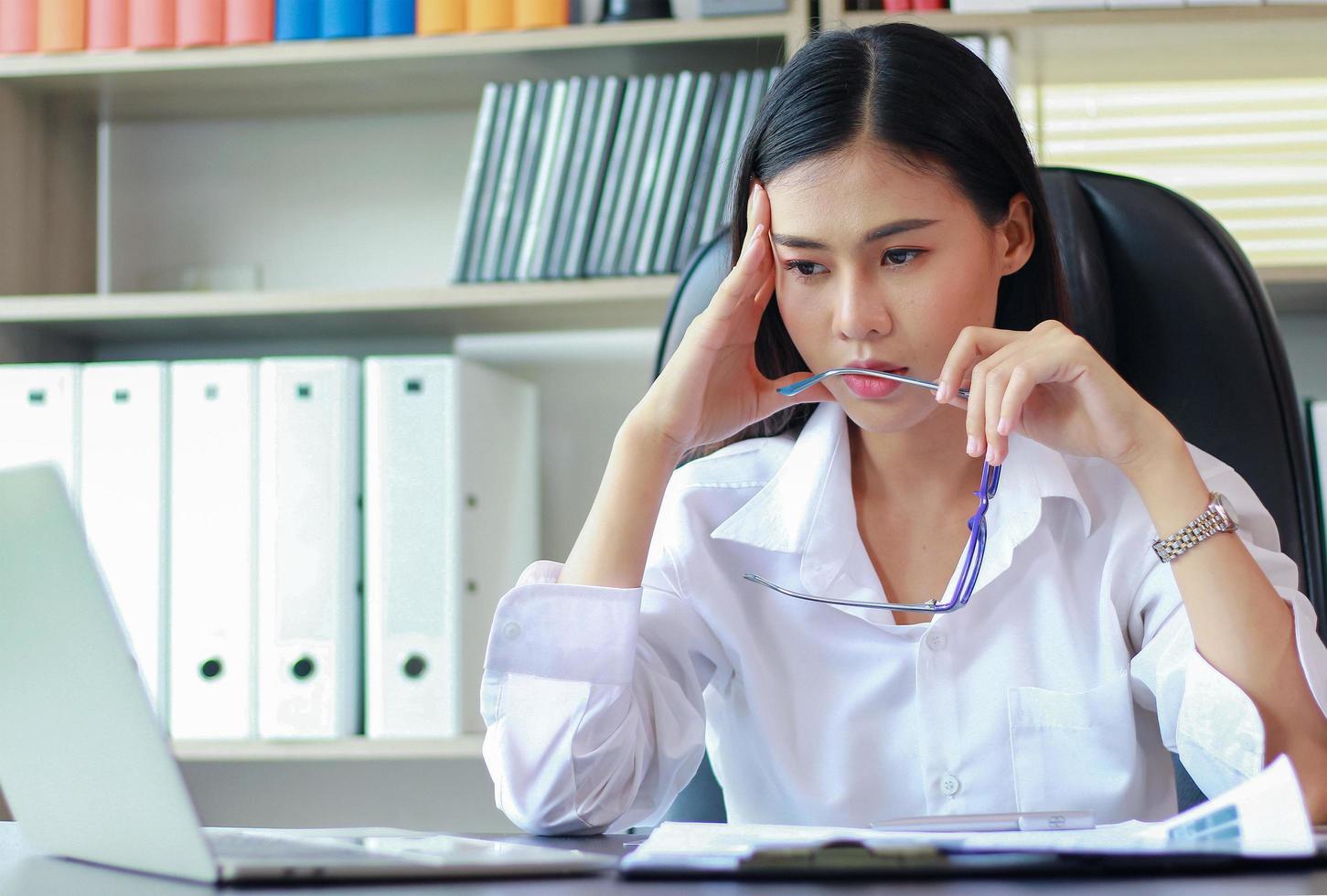 Porträt der asiatischen Frau in einem Anzug, der im Büro sitzt und über Marketing nachdenkt foto