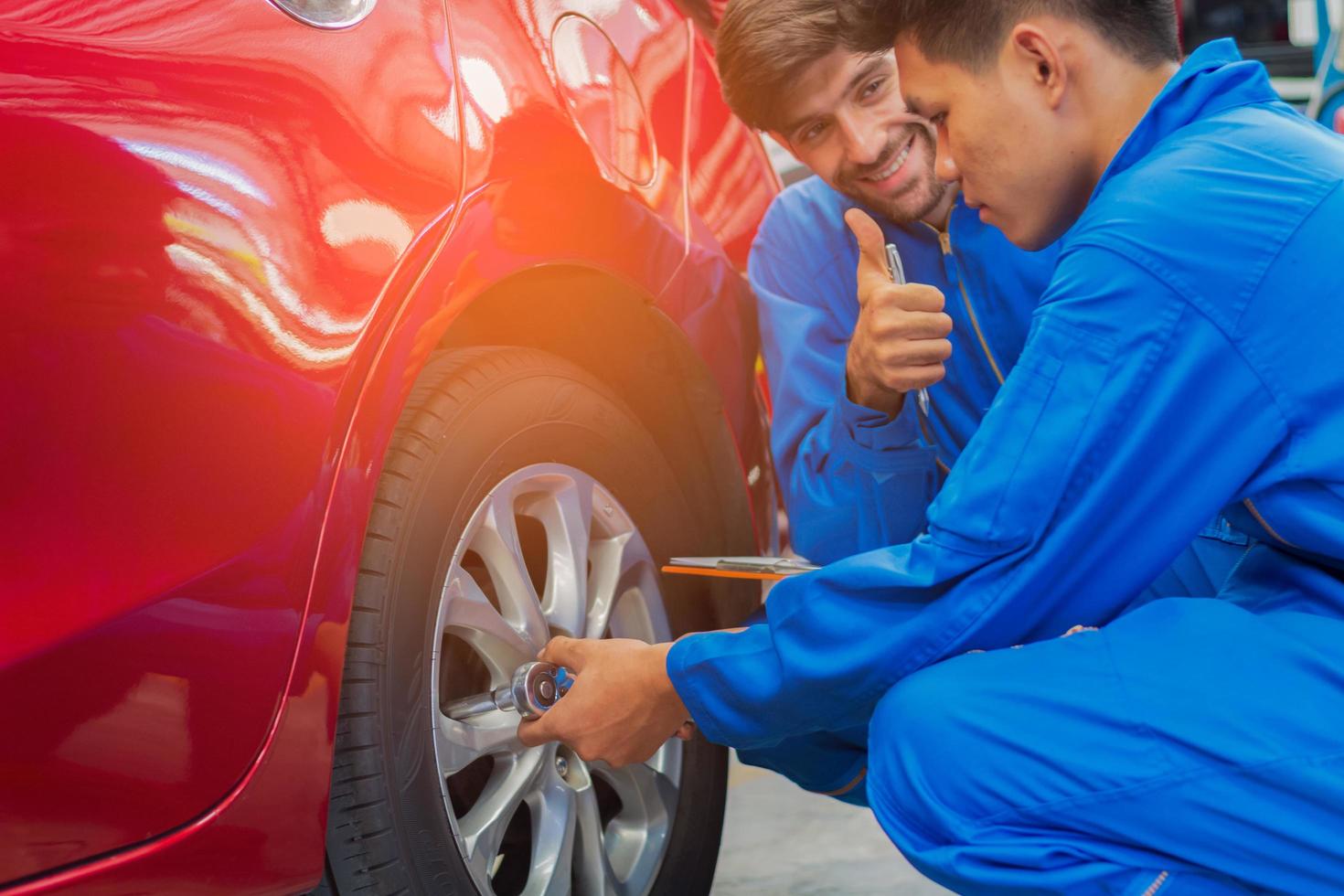 Der Mechaniker in der Autowerkstatt überprüft den Zustand der Räder und des Motors foto