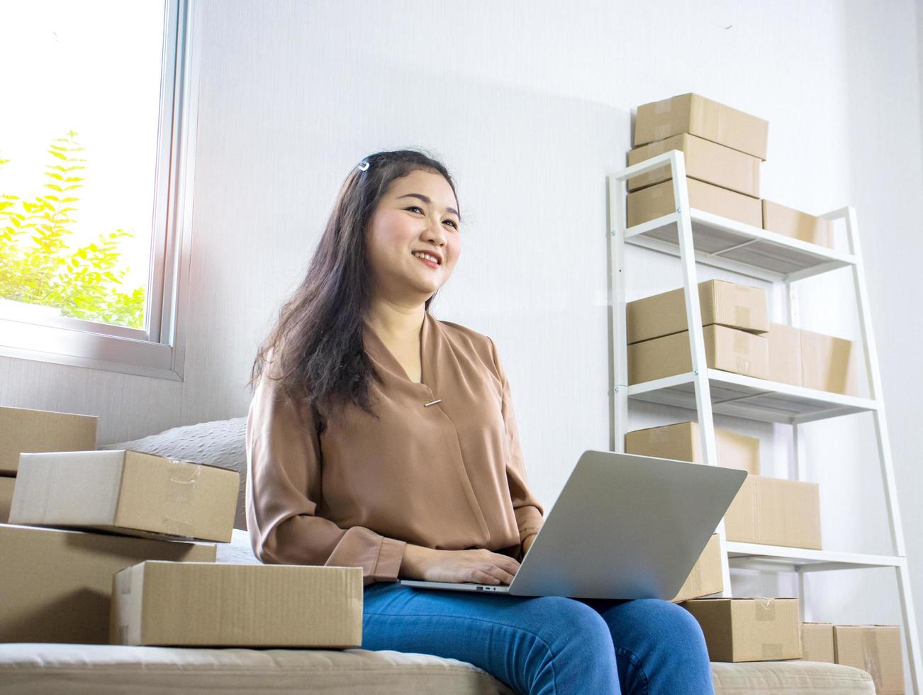 schöne asiatische Frau, die zu Hause sitzt und online arbeitet, Versandgeschäft online foto