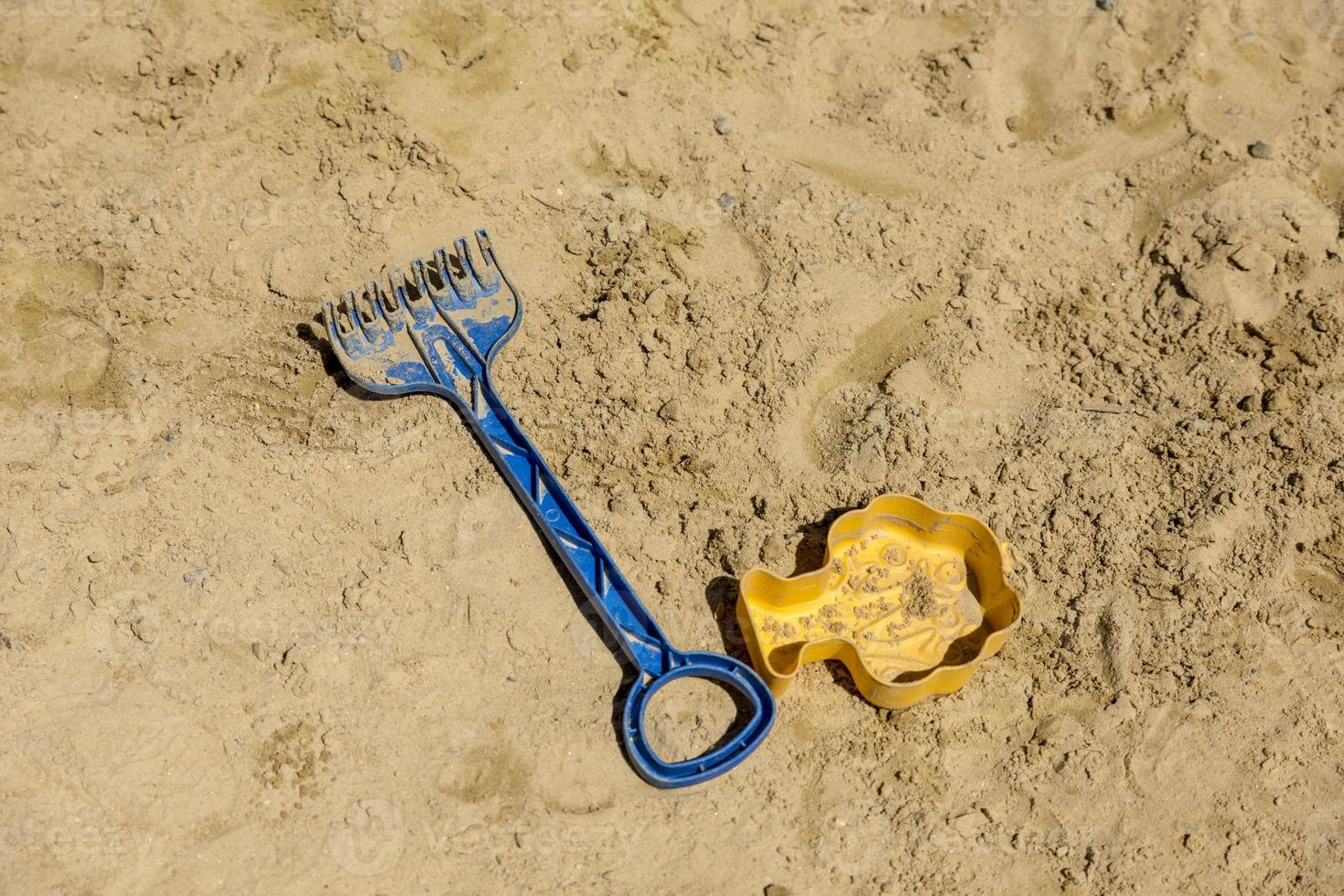 Kinderspielzeugschaufel und Sandform liegen auf Sand foto