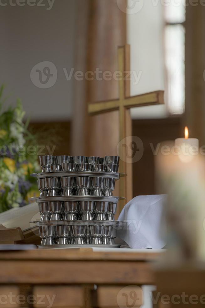 Das Kirchenkreuz steht auf einem Altar mit einem Kommunionbecher und einer verschwommenen brennenden Kerze foto