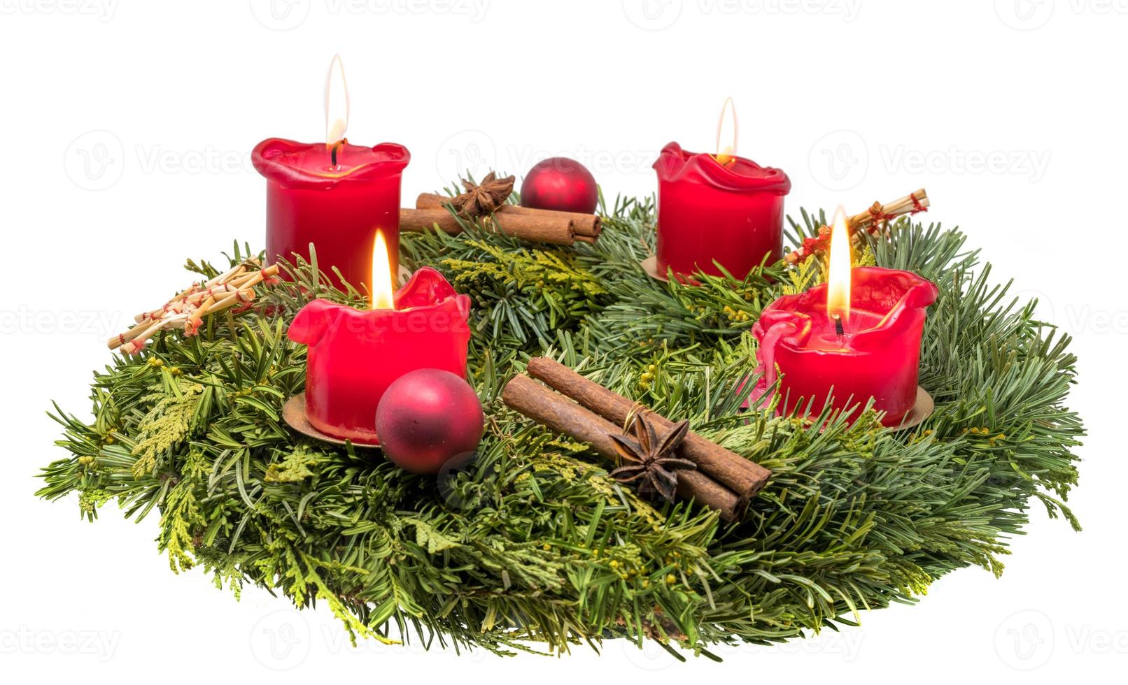 geschmückter Adventskranz aus Tannenzweigen mit brennenden roten Kerzen foto