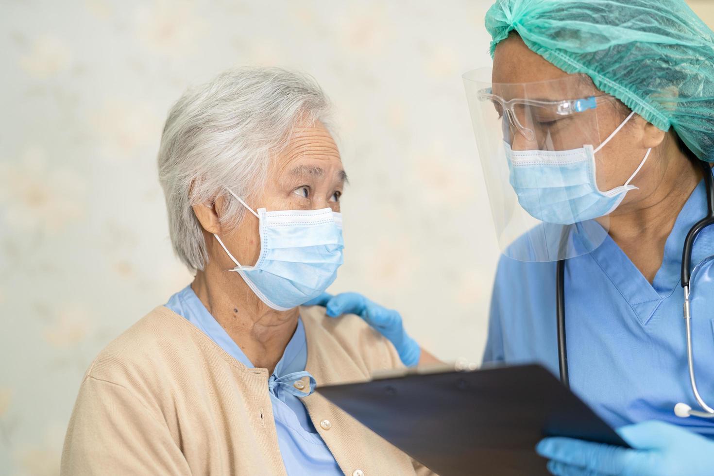 Arzt verwendet Stethoskop, um asiatische ältere oder ältere alte Frau Patientin zu überprüfen, die eine Gesichtsmaske im Krankenhaus trägt, um die Infektion zu schützen covid 19 Coronavirus foto