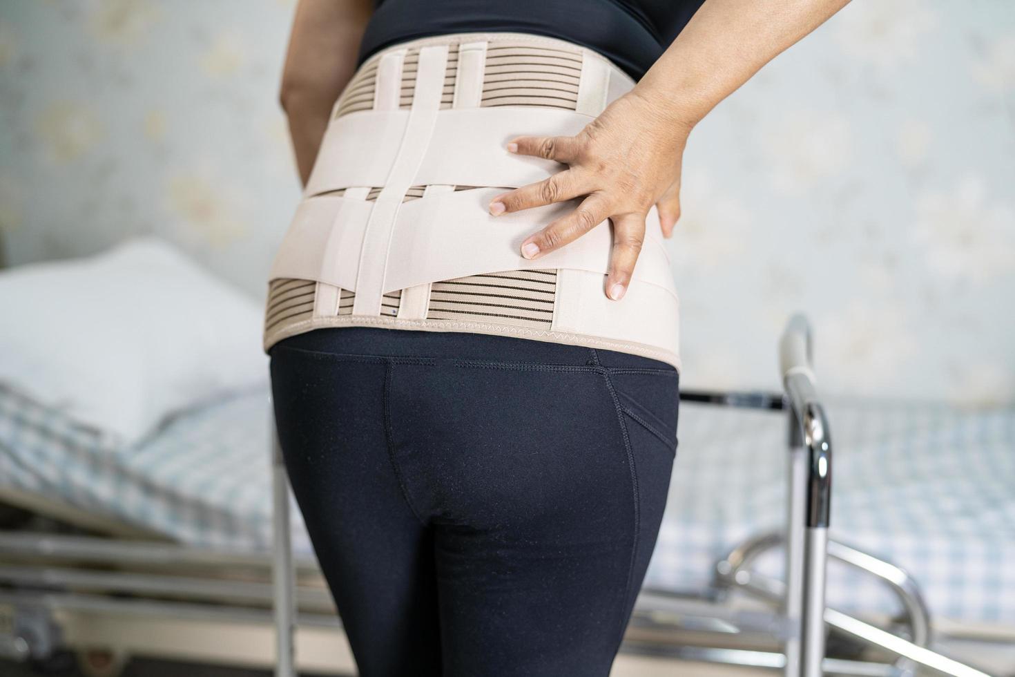 asiatische Patientin mit Rückenschmerzen Stützgürtel für orthopädische Lendenwirbelsäule mit Gehhilfe foto