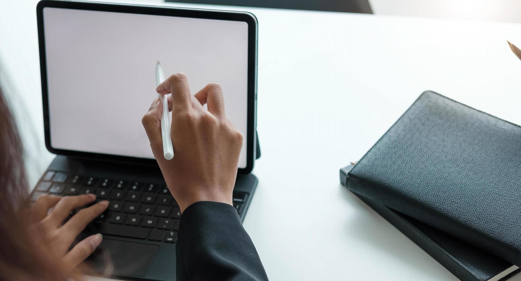 Geschäftsfrau, die mit einem Stift auf einem digitalen Tablett mit einem Laptop in einem modernen Büro arbeitet foto