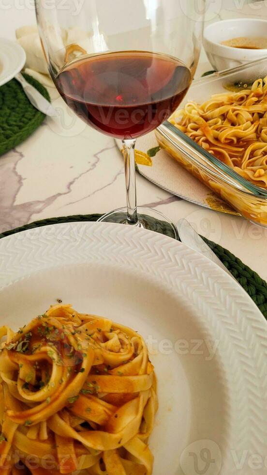 Abendessen mit Pasta und Glas von rot Wein foto