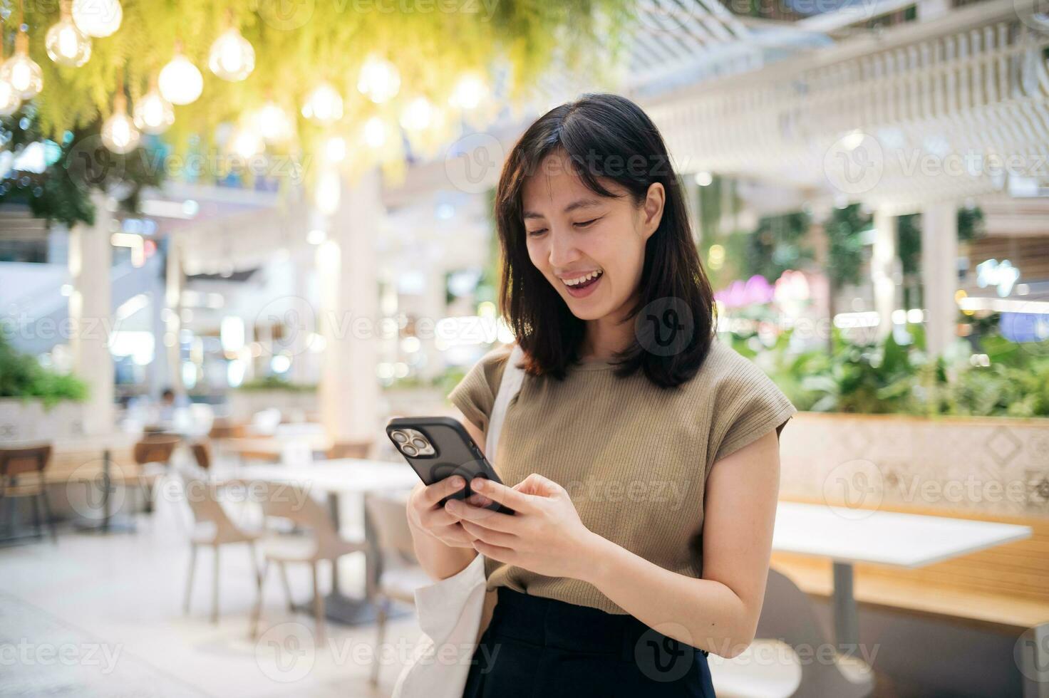 Porträt schön jung asiatisch Frau mit Clever Handy, Mobiltelefon Telefon im Cafeteria beim Einkaufen Einkaufszentrum. foto